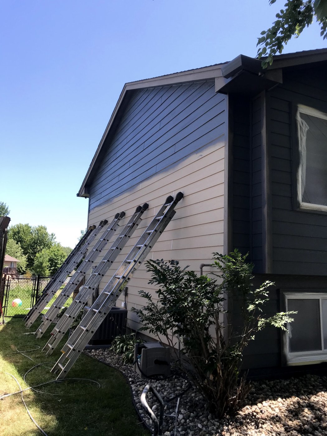 Exterior painting job in the Sioux Falls area — extension ladders set against a two-story home