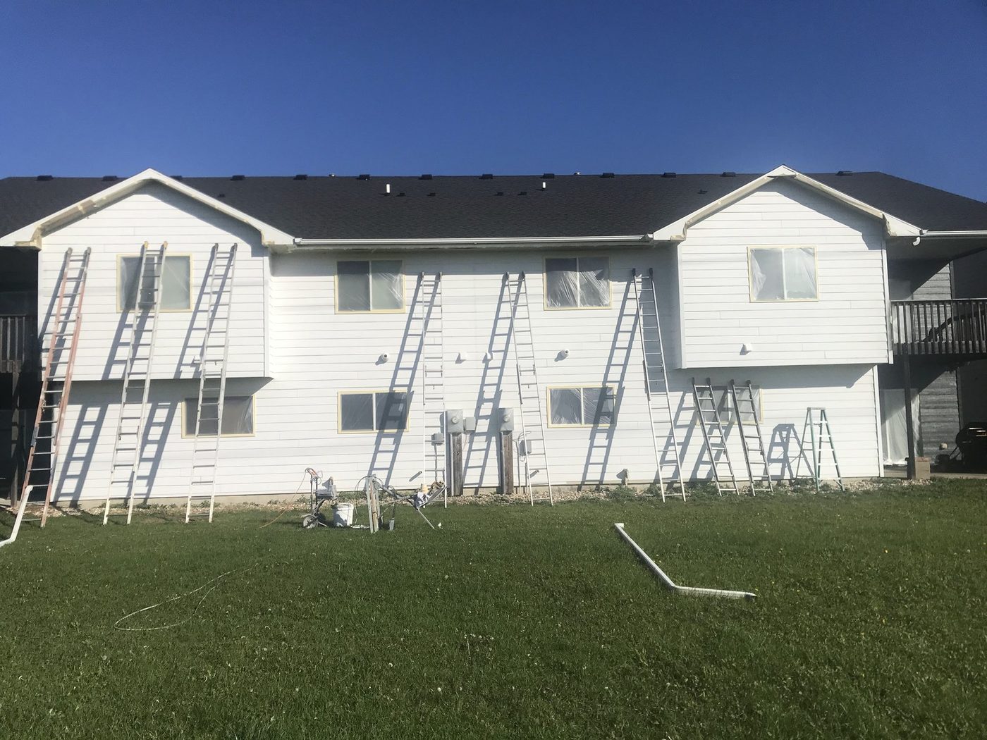 House Painting Sioux Falls crew mid-repaint on an apartment exterior, ladders set along the building