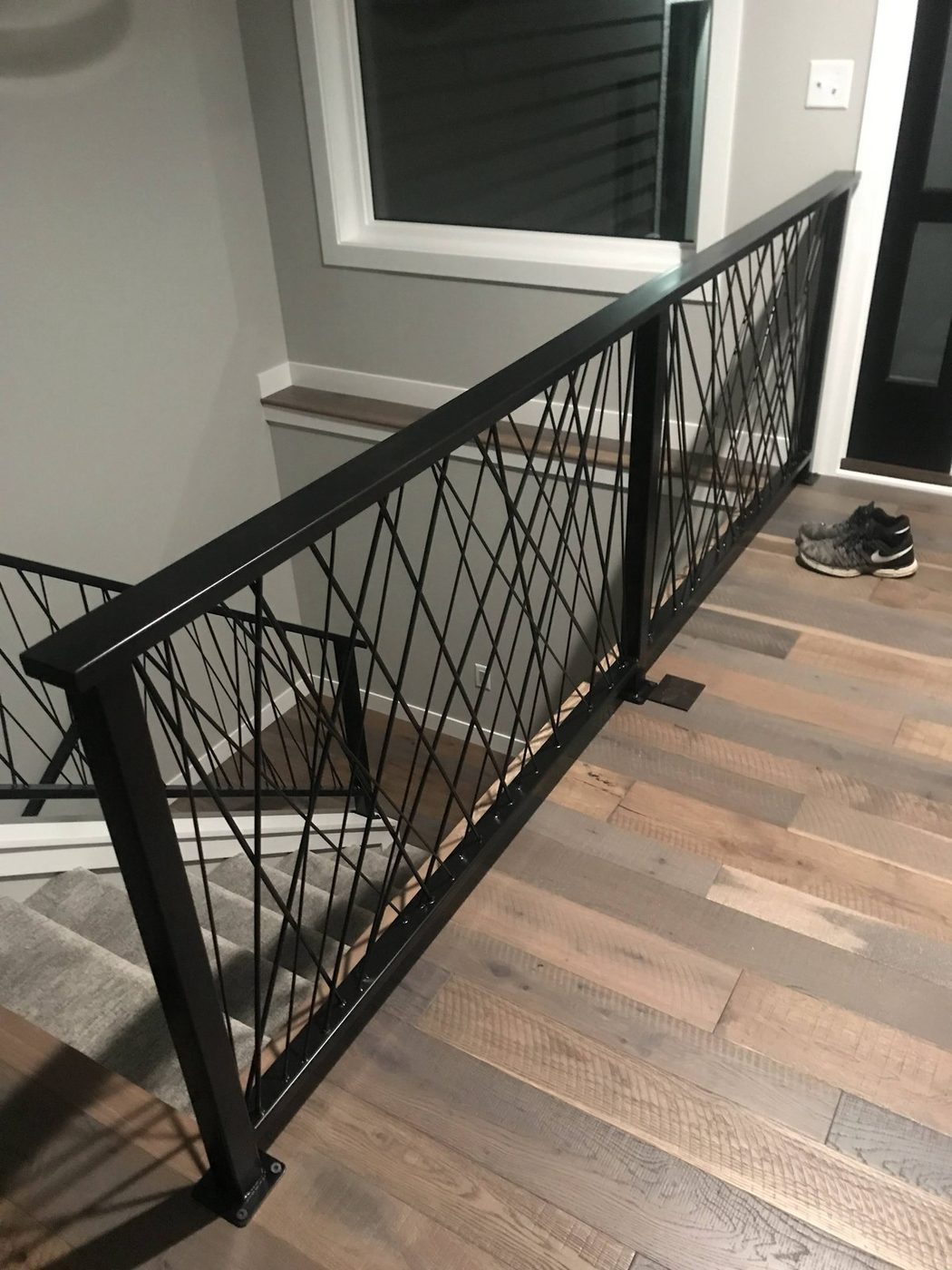 Black metal stair railing installed over refinished hardwood flooring